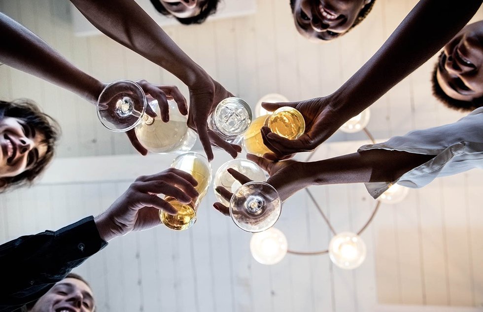 Group of friends making a toast, upward view of hands holding gl